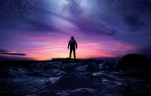 Silhouette of a man looking at the night sky filled with stars.