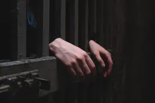 Uma pessoa atrás das grades da porta da prisão.