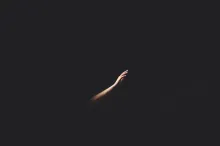Hand reaching out of the darkness upward