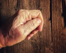 An old hand knocking on a old wooden door.