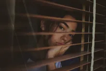 A sad looking woman gazing out a window.