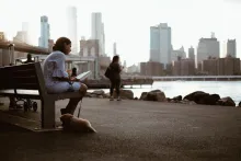 A woman sitting on a bench reading.