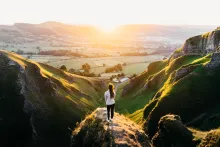 A woman standing on a hill watching the sunrise.