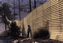 People standing by a border wall.