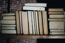several books stacked on a wooden shelf