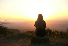 a woman looking at the sunset in the distant hills