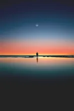 A calming image of a man silhouetted against a serene sunset on the beach