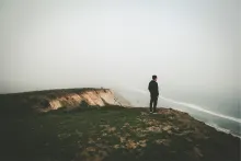 A man looking over a cliff toward the ocean.