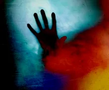 A photos illustration of a hand through red smoke.