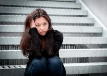 A women sitting on steps holding her head.