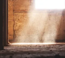A an empty room with a brick walls and sunlight coming in from a window.