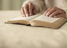 Older hands on top of a Bible.