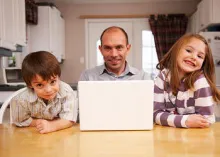 A dad sitting with two kids at a table.