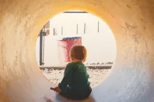 A little boy in a large concrete drain tube playing.