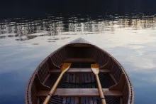 An empty wooden boat with two wooden oars.