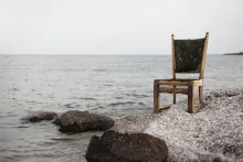 A chair sitting by a lake.