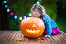 A little girl looking side a carved pumpkin jack o latern