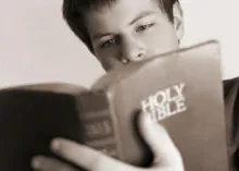 A teenage boy reading the Holy Bible.