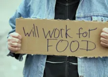 A man holding a "will work for food" sign.