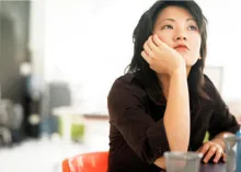 A woman with her head resting on her hand and looking thoughtfully.