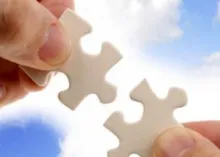 Hands Holding Jigsaw Puzzle Pieces In Front Of Blue Sky