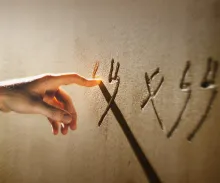 A hand writing on a stone wall.