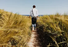 A woman walking on a path with tall grass around her.