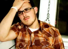 A sad looking young adult male with his hand on head.