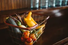 A wire shopping basket full of vegetables.