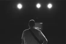 The back of a man looking at stage lights.