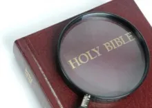 Magnifying glass over the words Holy Bible.