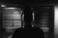 An upclose photo of a man but his face cannot be seen because of a shadow.