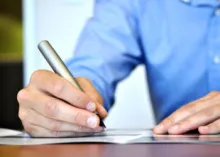 man writing with pen and paper