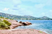 water by a red coast with a city in the background