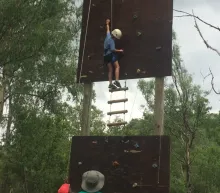 Youth climbing a rope ladder and rock wall