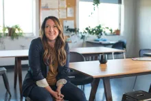a smiling woman sitting in a chair next to a wooden table
