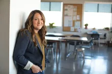 a professionally, dressed woman leaning against the wall of a meeting room