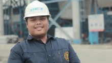a man wearing a hard hat standing in front of a construction site