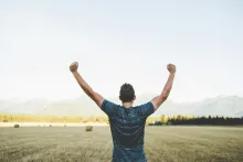 Man with arms in the air looking out at a field