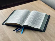 an open Bible on a light-colored wood table