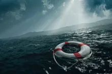 A life preserver ring floating in rough waters with sunlight coming through the clouds.