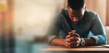 A man praying at a table.