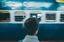 Young man facing away looking at a passing subway