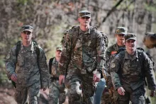 a group of young men wearing army camouflage uniforms and walking outdoors