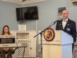 a woman seated at a piano keyboard and a man standing at a lectern