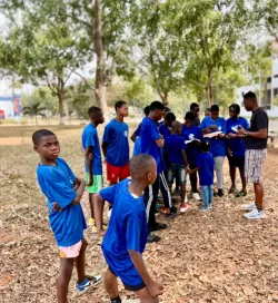 a group of boys standing outdoors wearing matching blue shirts