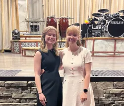 two ladies standing in front of a stage with musical instruments on the stage