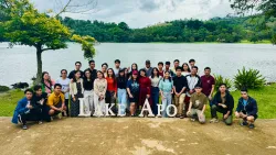 a group of people standing in front of a lake with a sign "Lake Apo" in front of them