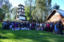 a large group of people gathered on the lawn in front of two buildings