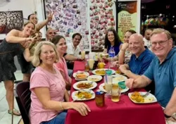 a group of people sitting and standing around a table with food